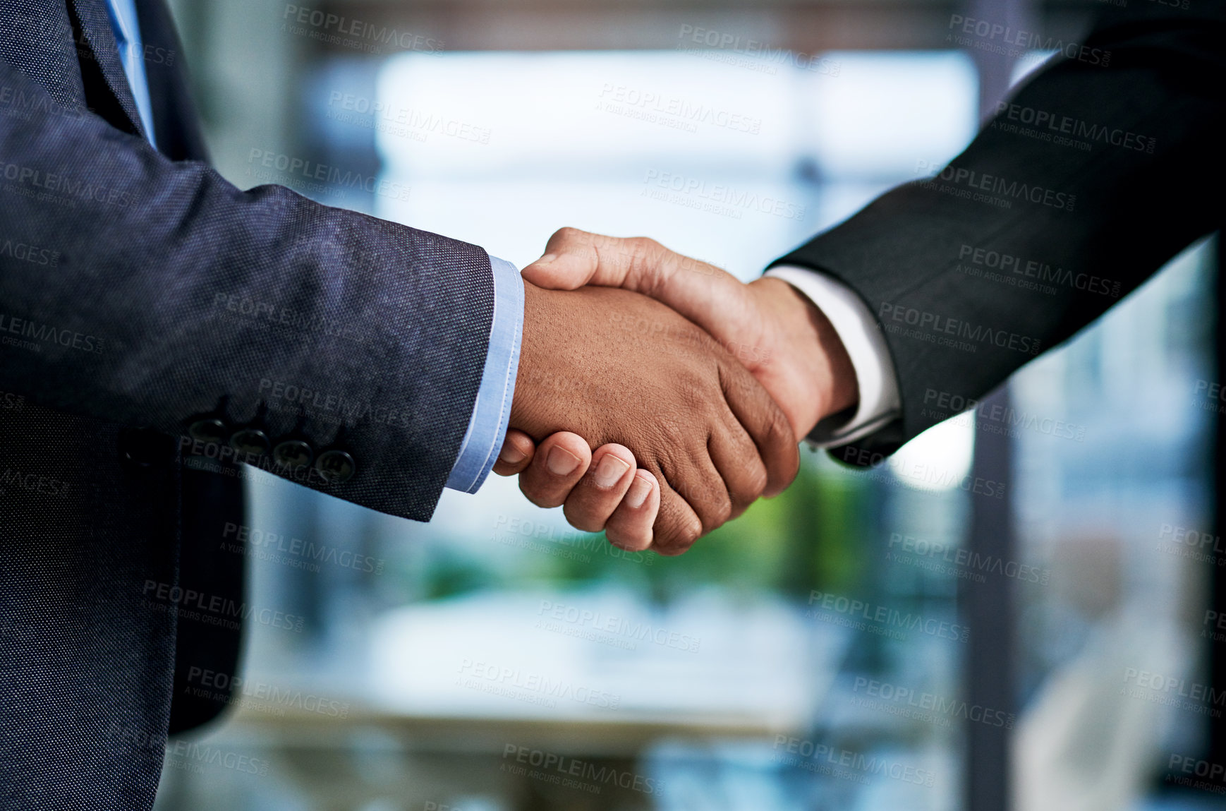 Buy stock photo Cropped shot of two unrecognizable businesspeople shaking hands in a modern office