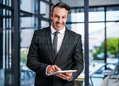 Buy stock photo Cropped portrait of a handsome mature businessman smiling while using a digital tablet in a modern office