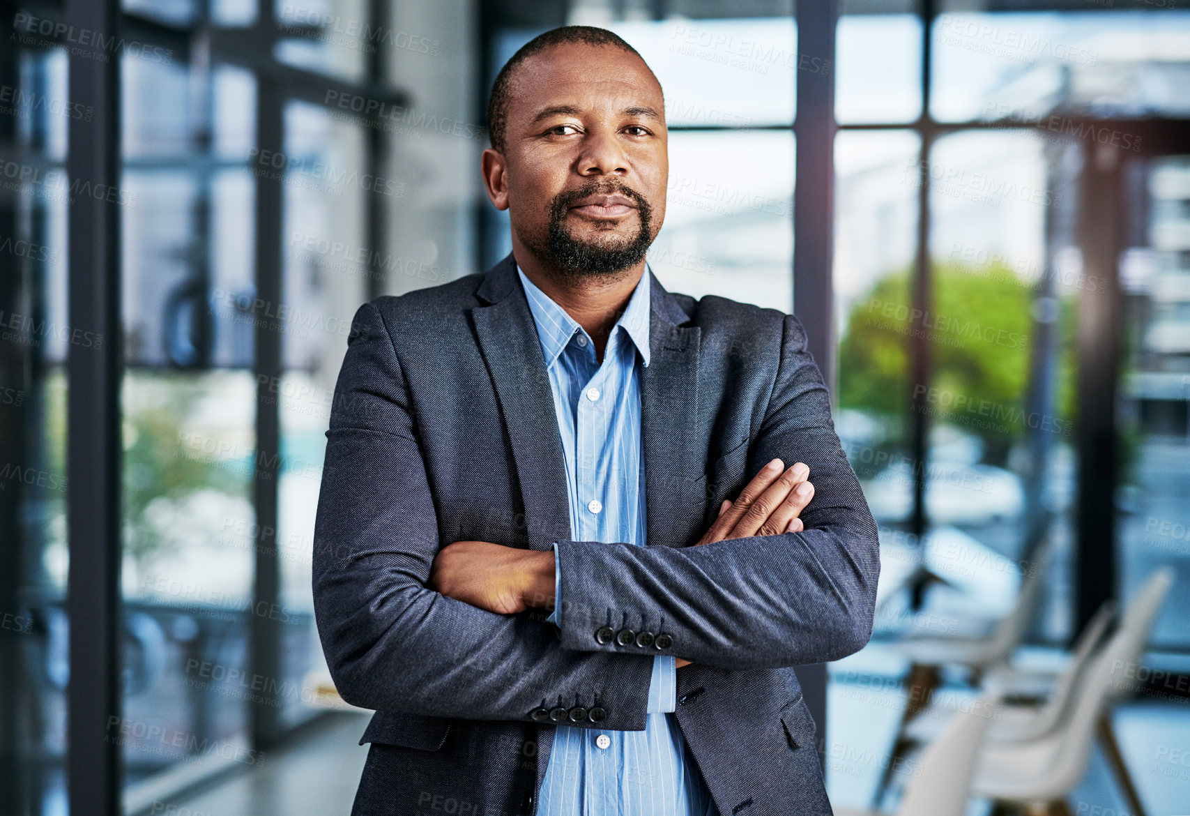 Buy stock photo Cropped portrait of a handsome middle aged businessman standing with his arm folded in a modern office