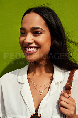 Buy stock photo Cropped shot of an attractive young woman standing alone against a green background during a day out in the city