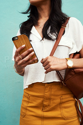 Buy stock photo Cropped shot of an unrecognizable woman standing alone against a blue background and texting while in the city