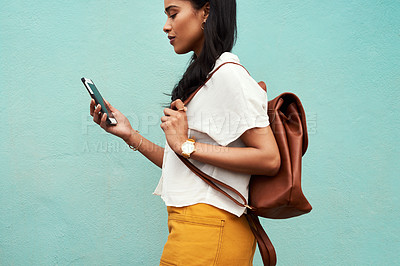 Buy stock photo Cropped shot of an unrecognizable woman standing alone against a blue background and texting while in the city