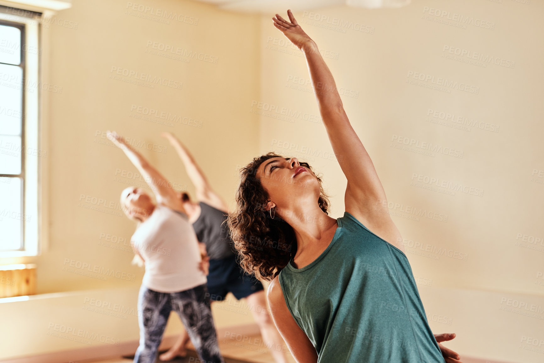 Buy stock photo Shot of a group of young men and women practicing yoga in a fitness class