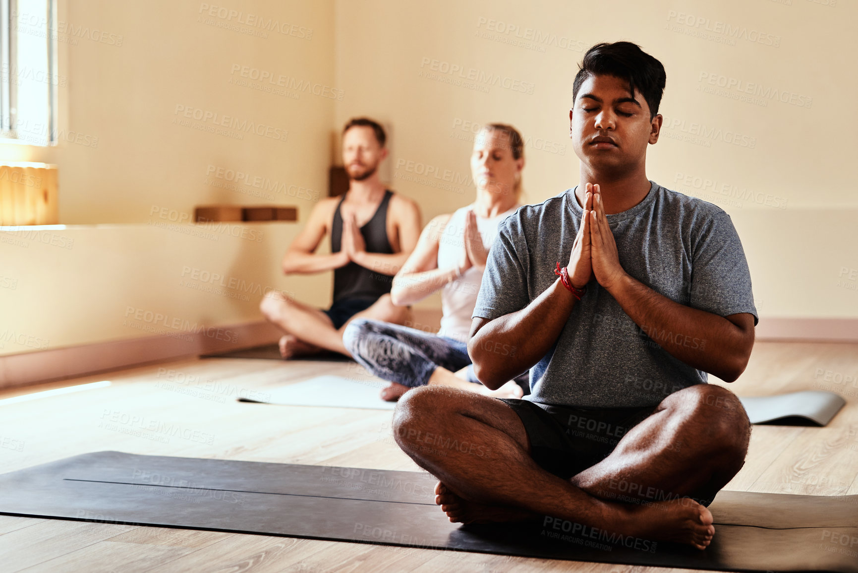 Buy stock photo Shot of a group of young men and women meditating in a yoga class