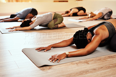 Buy stock photo Shot of a group of young men and women practicing the child’s pose during a yoga session