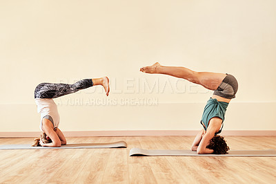 Buy stock photo Shot of two young women doing headstands in a yoga class