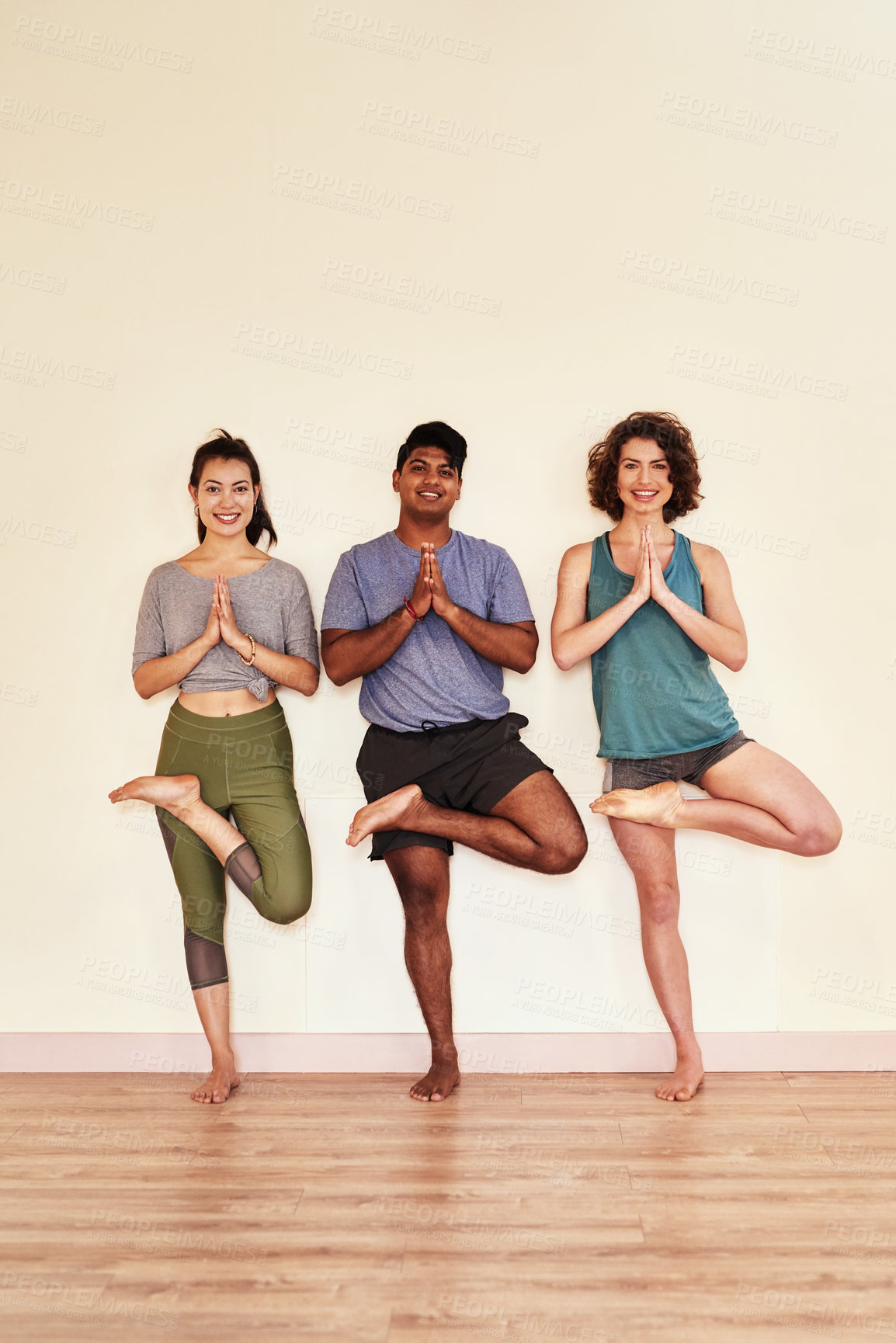 Buy stock photo Shot of a group of young men and women practicing the tree pose during a yoga session