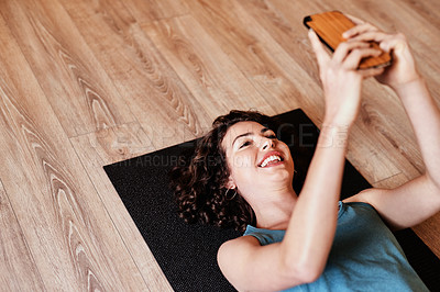 Buy stock photo Shot of a young woman using a smartphone during a yoga session