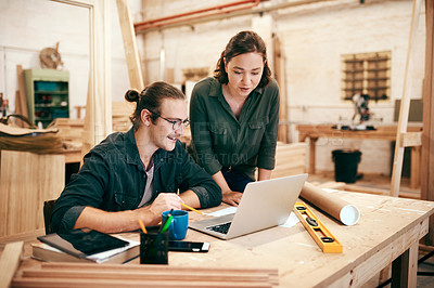 Buy stock photo Cropped shot of two young carpenters planning and working on a laptop together inside their workshop