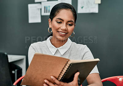 Buy stock photo Shot of a young businesswoman writing in a notebook while working in an office
