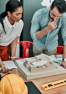 Buy stock photo Shot of two architects working together on a scale model of a building in an office