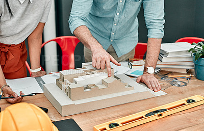 Buy stock photo Closeup shot of two architects working together on a scale model of a building in an office