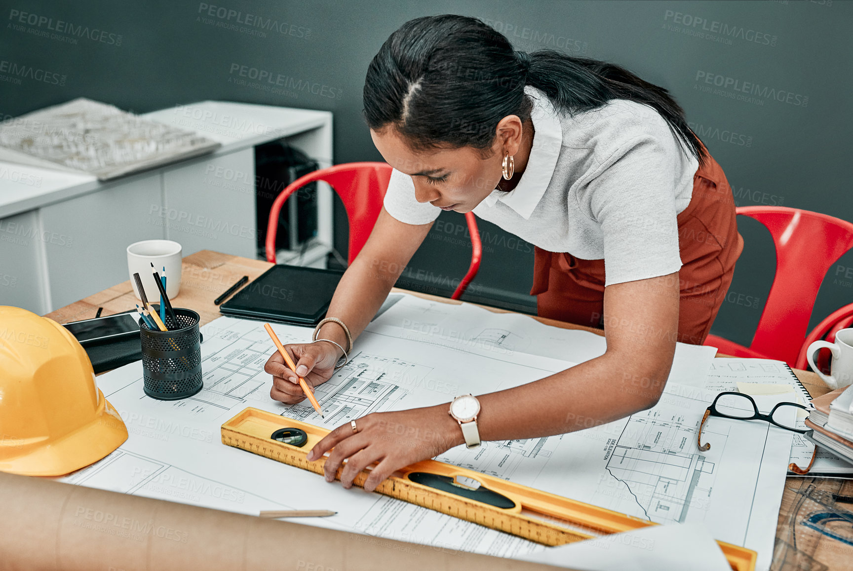Buy stock photo Shot of a young architect working with blueprints in an office