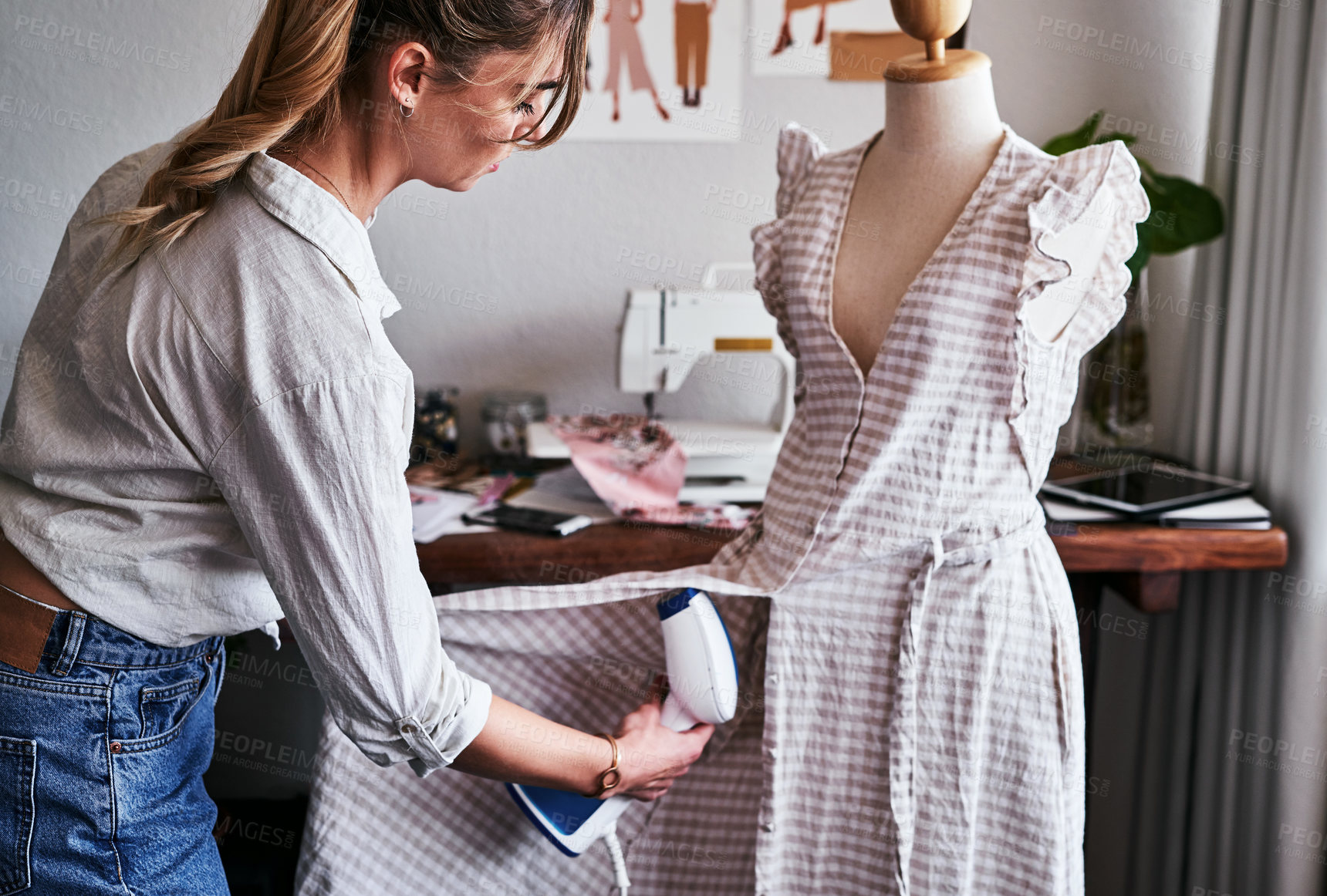 Buy stock photo Shot of a fashion designer using  a garment steamer in her workshop