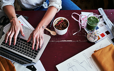 Buy stock photo Cropped shot of a fashion designer having breakfast while working at her desk