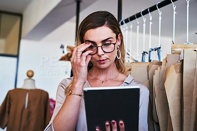 Buy stock photo Cropped shot of a young fashion designer using a digital tablet at work
