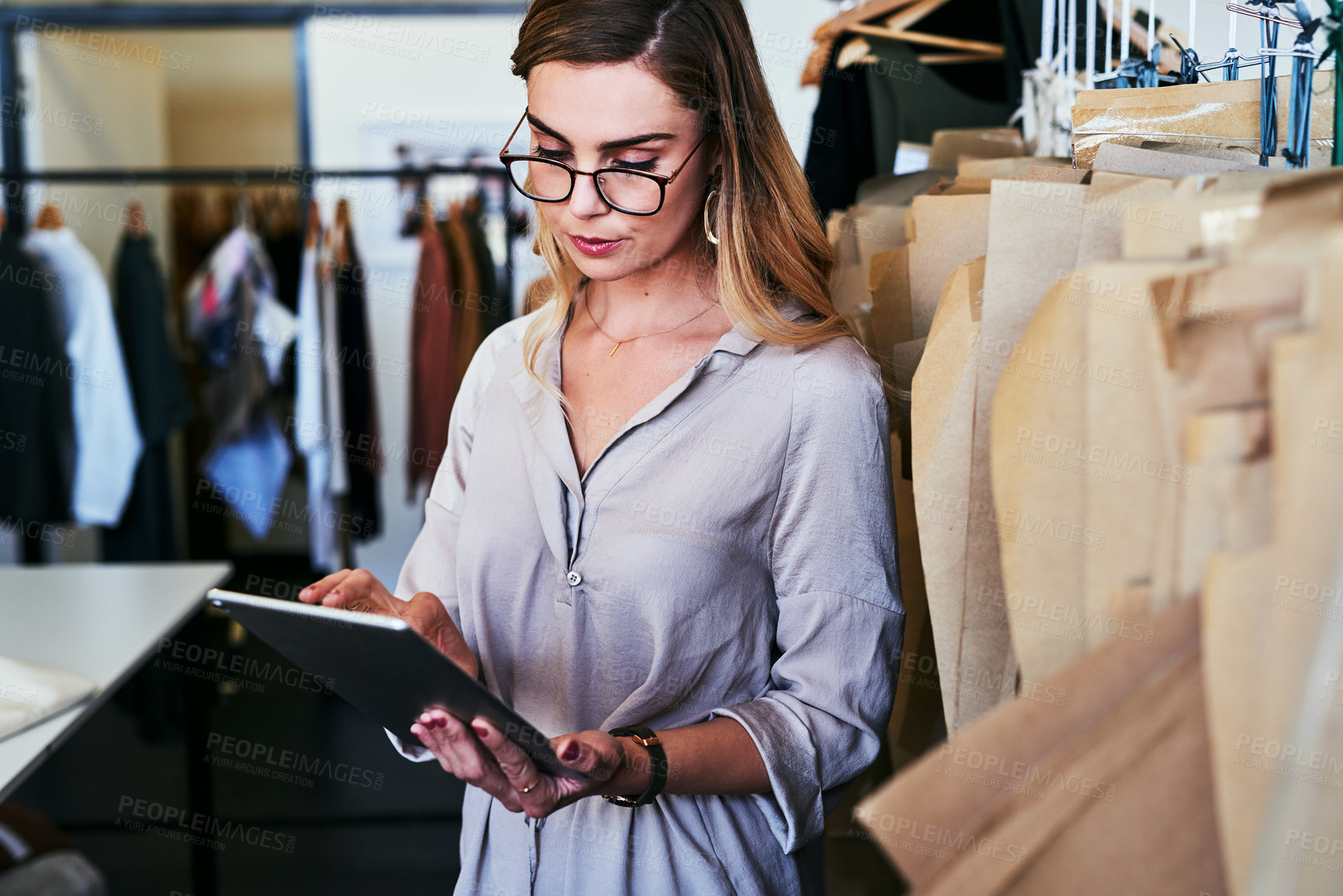 Buy stock photo Cropped shot of a young fashion designer using a digital tablet at work