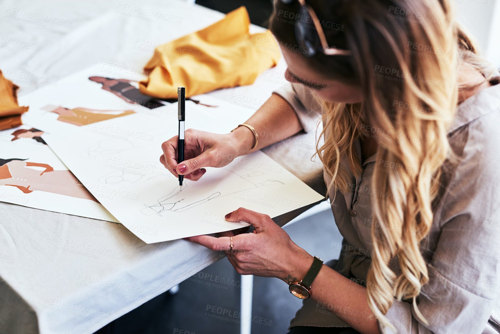 Buy stock photo Cropped shot of a fashion designer working on new sketches at her desk