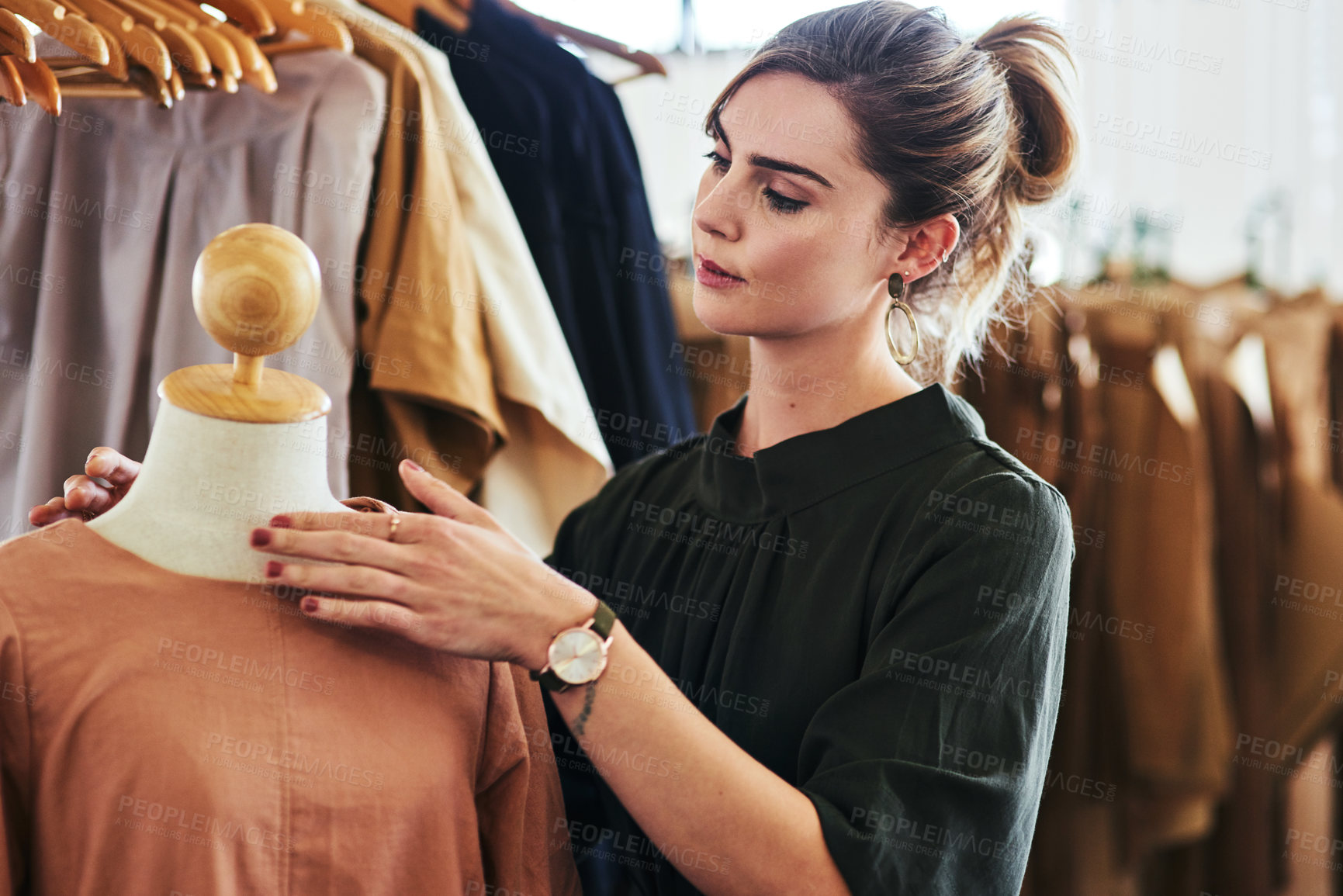 Buy stock photo Shot of a young fashion designer working on a garment hanging over a mannequin