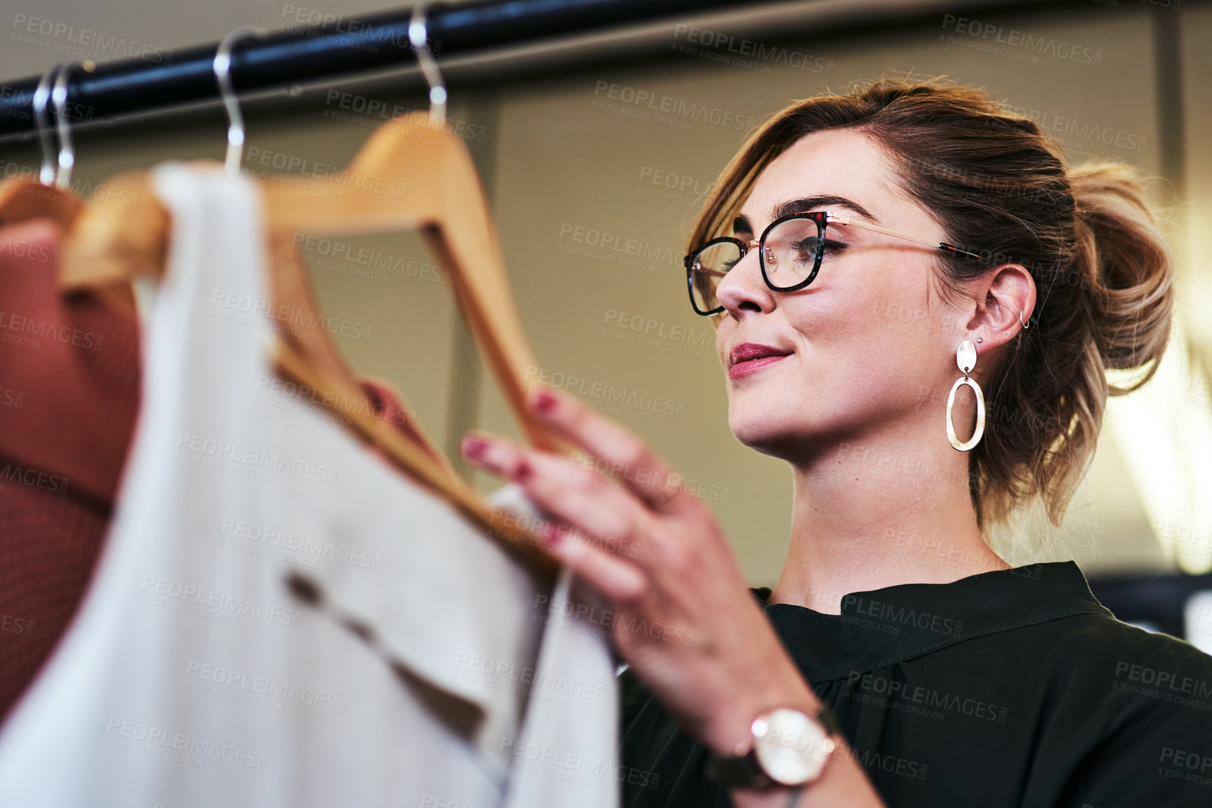 Buy stock photo Cropped shot of a designer looking at garments on a railing in her workshop