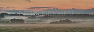 Buy stock photo Landscape view of fog over remote field with copy space at sunset. Mist covering a vast expanse of countryside meadow in Germany at dawn. Smoke from wildfire or bush fires rolling over nature reserve