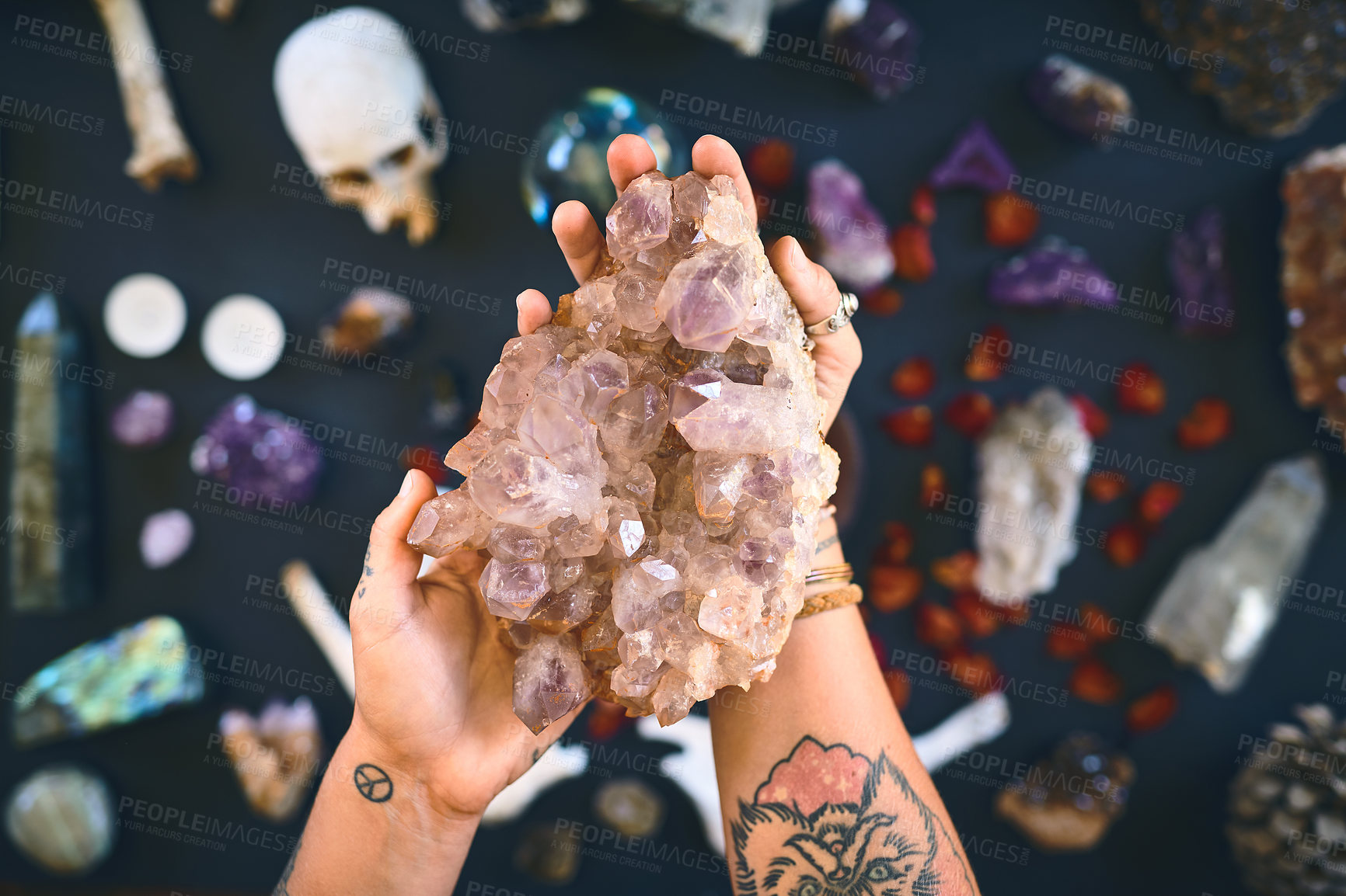Buy stock photo Closeup of an unrecognizable person holding a crystal with two hands over a table filled with more crystals inside during the day