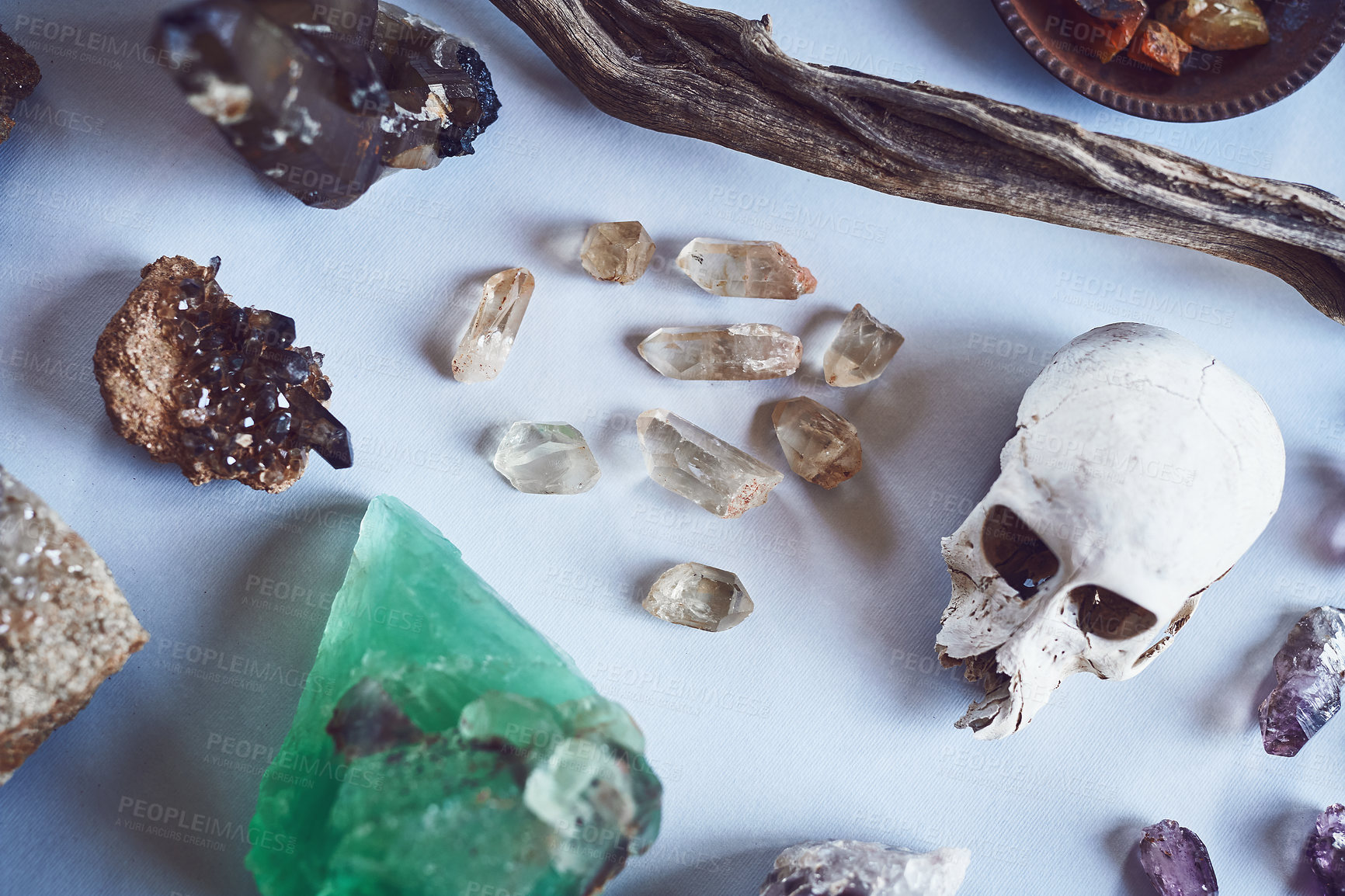 Buy stock photo High angle shot of a table filled with different types of crystals and a skull inside during the day