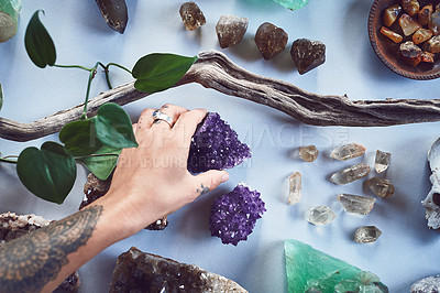 Buy stock photo Closeup of an unrecognizable person holding a crystal with two hands over a table filled with more crystals inside during the day