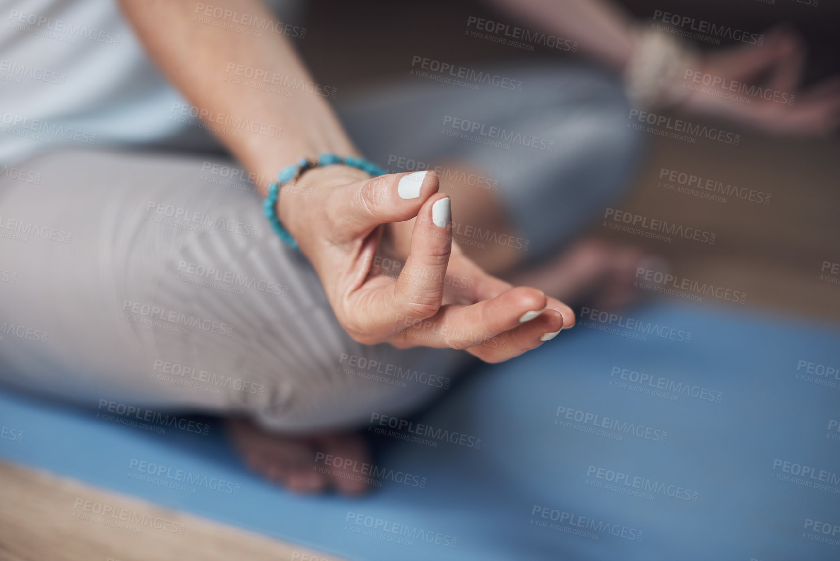 Buy stock photo Cropped shot of an unrecognizable woman sitting indoors alone and meditating with her hand in a gyan mudra
