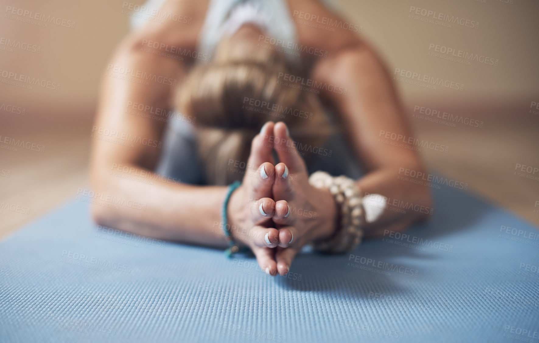 Buy stock photo Cropped shot of an unrecognizable woman holding a child's pose during an indoor yoga session alone