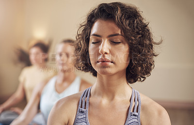 Buy stock photo Cropped shot of a young group of women sitting together and meditating after an indoor yoga session