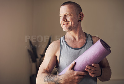 Buy stock photo Cropped shot of a handsome young man standing alone and holding his yoga mat before an indoor yoga session