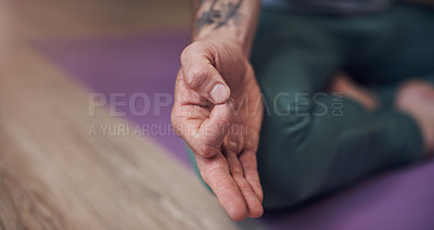 Buy stock photo Cropped shot of an unrecognizable man sitting indoors alone and meditating with his hand in a gyan mudra