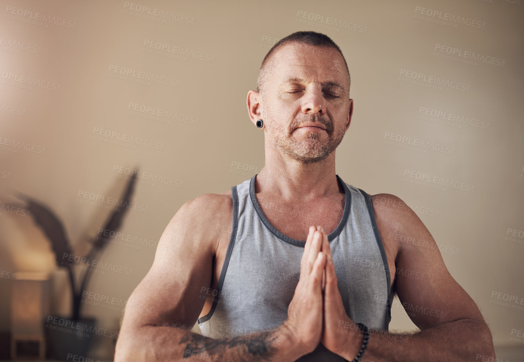 Buy stock photo Cropped shot of a handsome young man sitting alone and meditating during an indoor yoga session