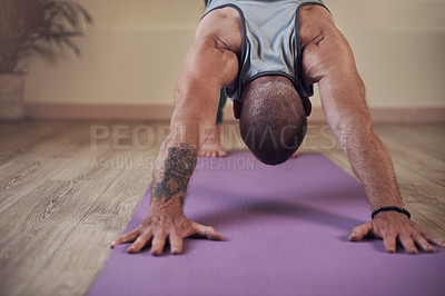 Buy stock photo Cropped shot of an unrecognizable man holding a downward facing dog pose during an indoor yoga session alone