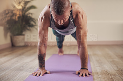 Buy stock photo Cropped shot of a handsome young man holding a high plank pose during an indoor yoga session alone