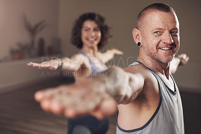 Buy stock photo Cropped shot of a handsome young man holding a warrior two pose during an indoor yoga class