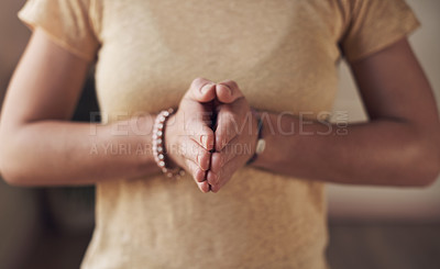 Buy stock photo Cropped shot of an unrecognizable woman standing with her palms together while meditating indoors
