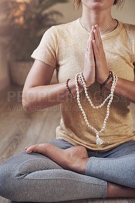 Buy stock photo Cropped shot of an unrecognizable woman sitting indoors and using mala beads during her meditation routine