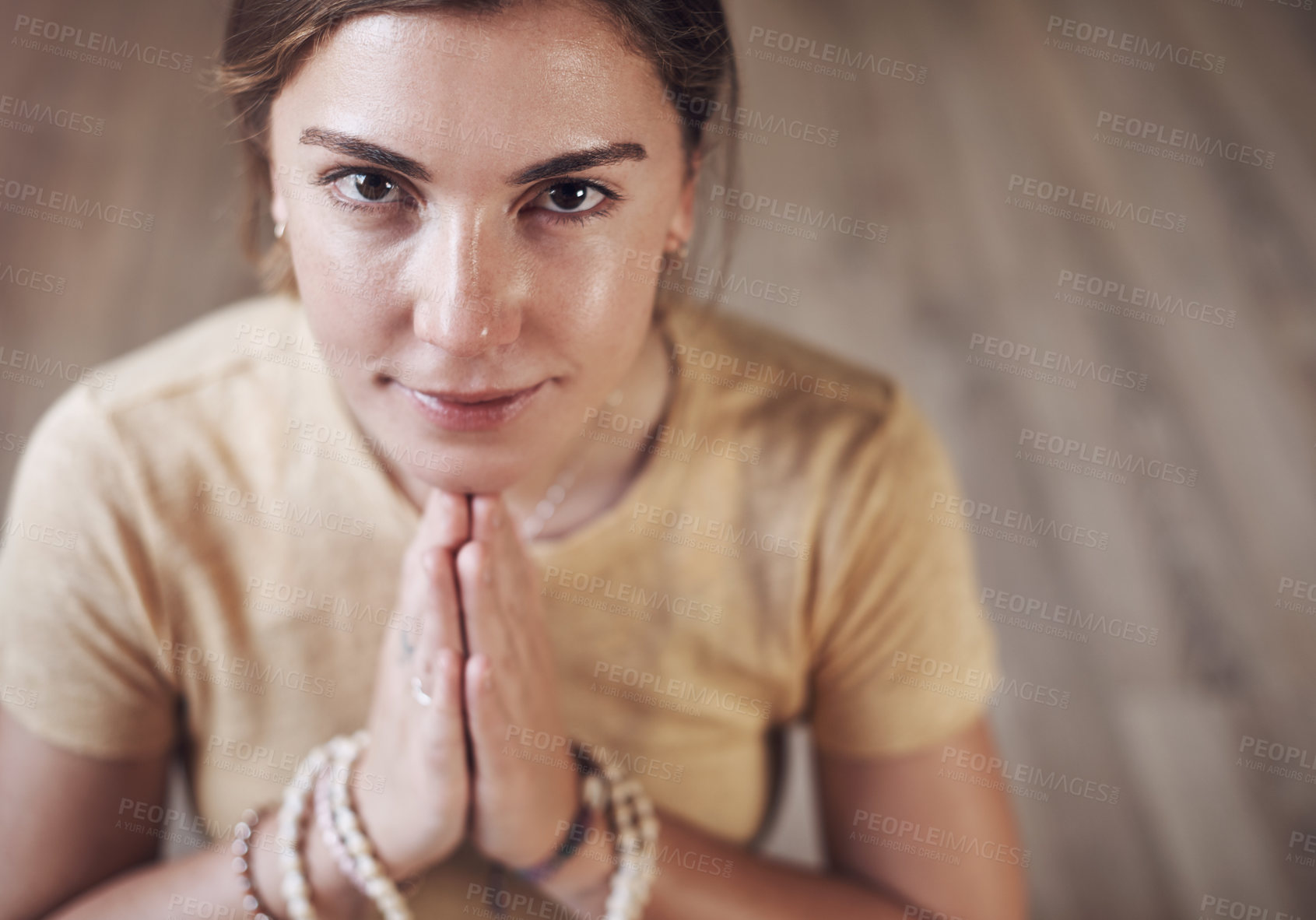 Buy stock photo Cropped portrait of an attractive young woman sitting indoors and using mala beads during her meditation routine
