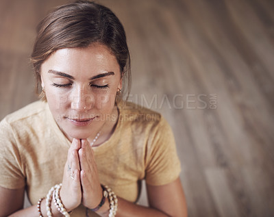 Buy stock photo Cropped shot of an attractive young woman sitting indoors and using mala beads during her meditation routine