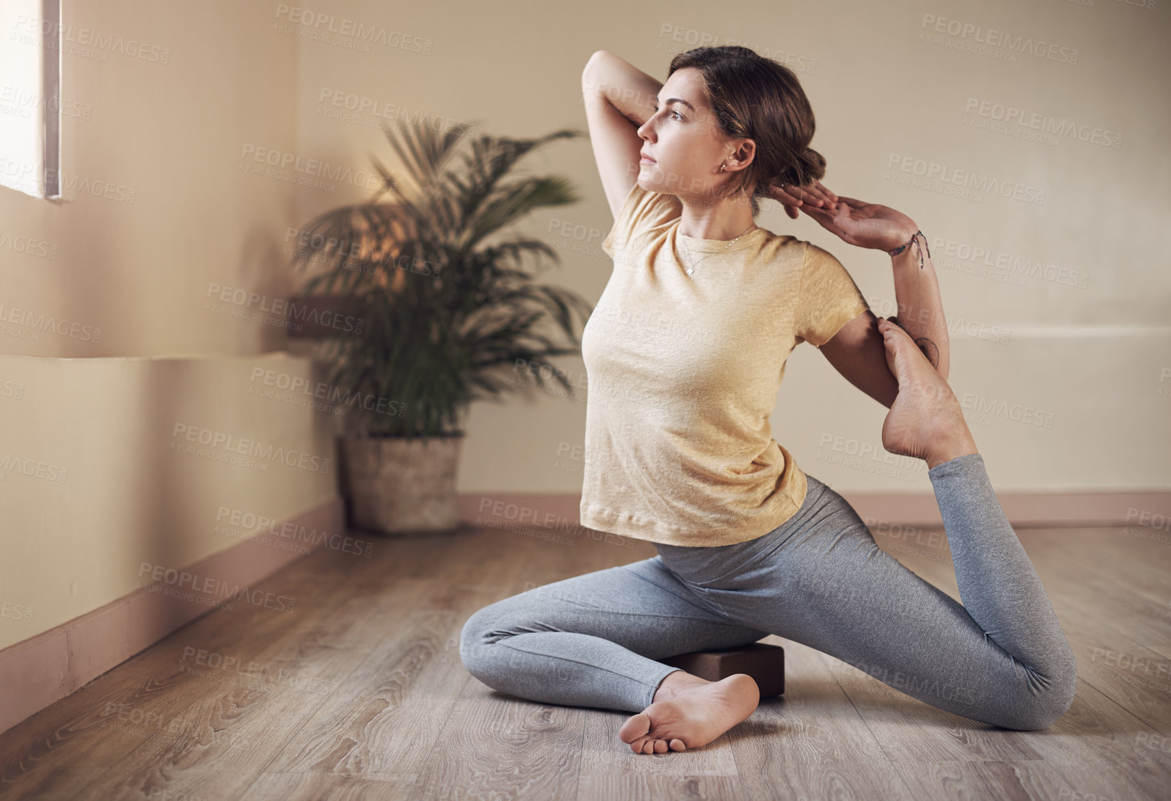Buy stock photo Full length shot of an attractive young woman holding a mermaid's pose during an indoor yoga session alone