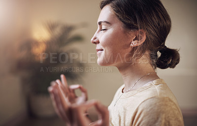 Buy stock photo Cropped shot of an attractive young woman sitting alone and meditating indoors