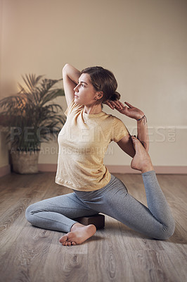 Buy stock photo Full length shot of an attractive young woman holding a mermaid's pose during an indoor yoga session alone