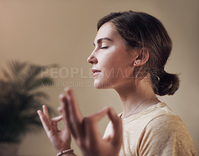Buy stock photo Cropped shot of an attractive young woman sitting alone and meditating indoors