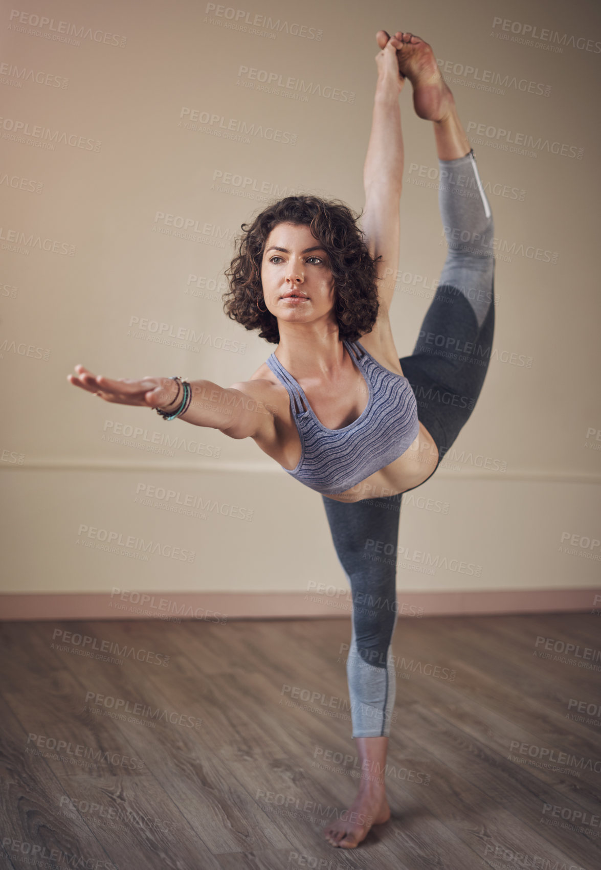 Buy stock photo Full length shot of an attractive young woman holding a dancer's pose while doing yoga alone indoors