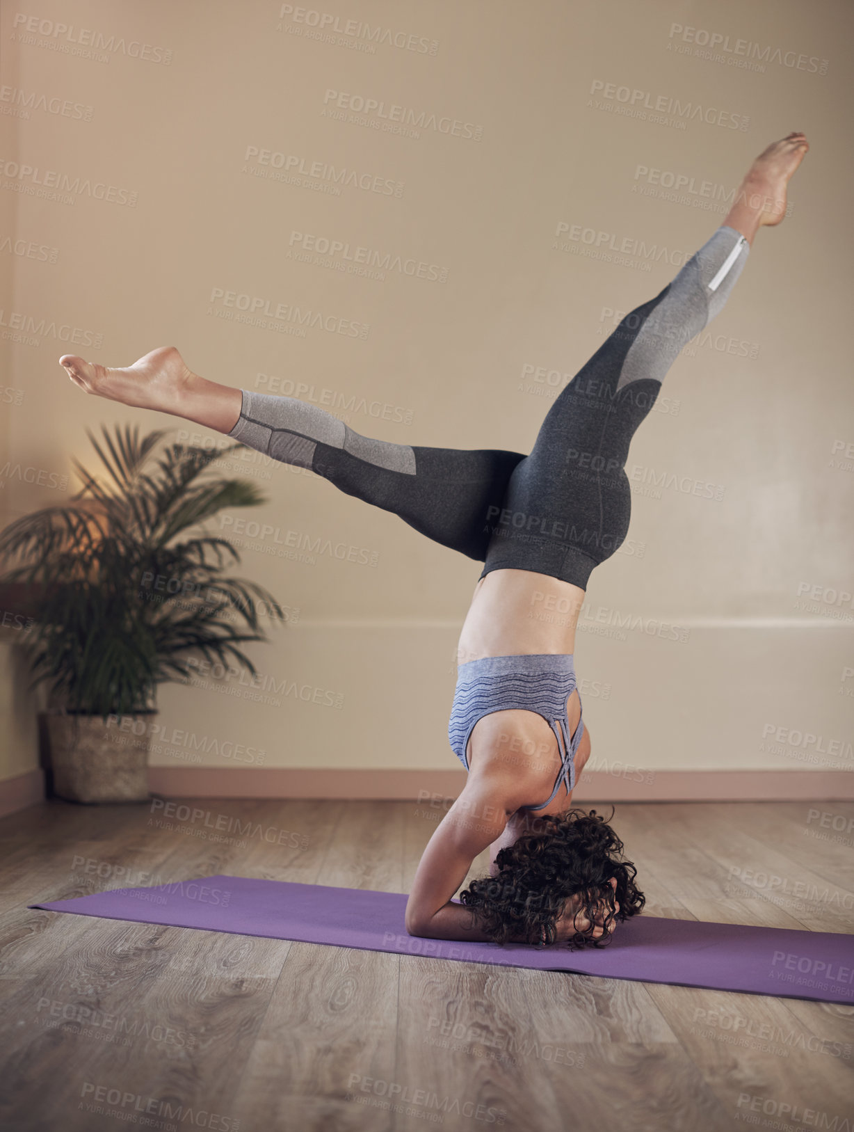 Buy stock photo Full length shot of an unrecognizable woman holding an elbow stand during an indoor yoga session alone
