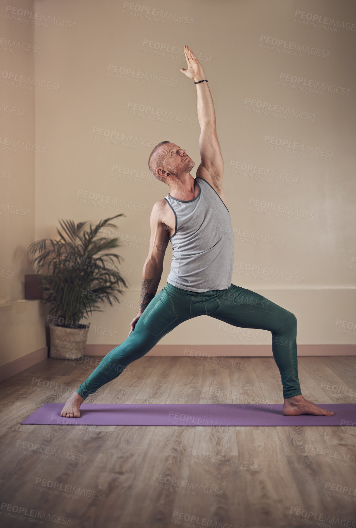 Buy stock photo Full length shot of a handsome young man standing and holding a yoga pose during an indoor session alone