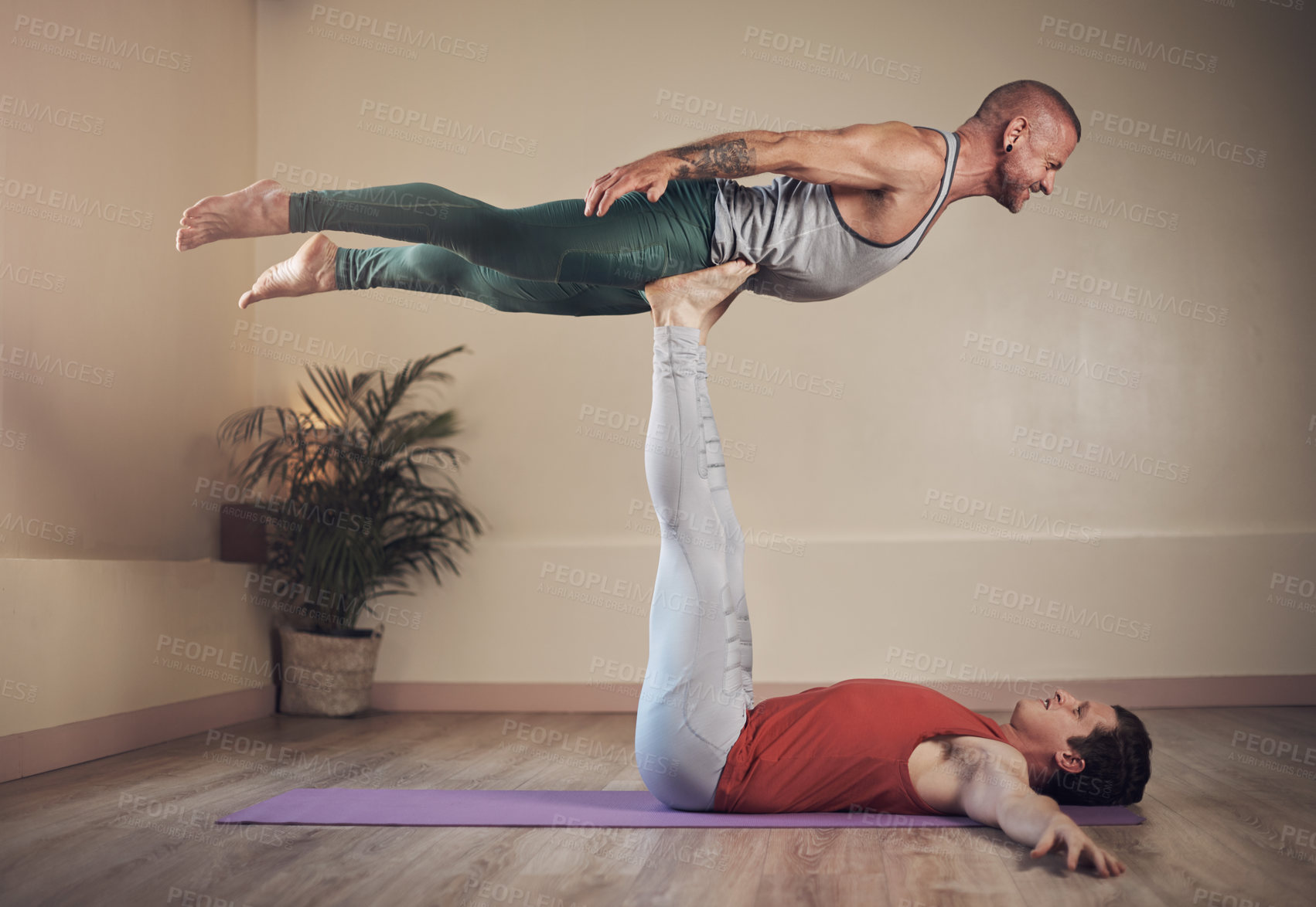 Buy stock photo Full length shot of a handsome young man doing acro yoga with his partner in a yoga studio