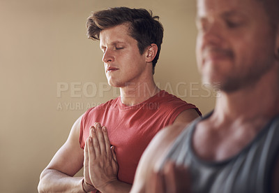 Buy stock photo Cropped shot of two young yogis standing together and meditating with their palms together after an indoor yoga session